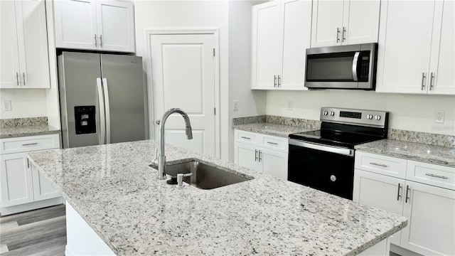 kitchen featuring white cabinets, sink, an island with sink, and stainless steel appliances