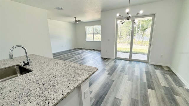 kitchen with light stone countertops, sink, decorative light fixtures, and plenty of natural light