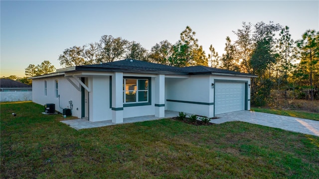 view of front facade with a lawn, cooling unit, and a garage