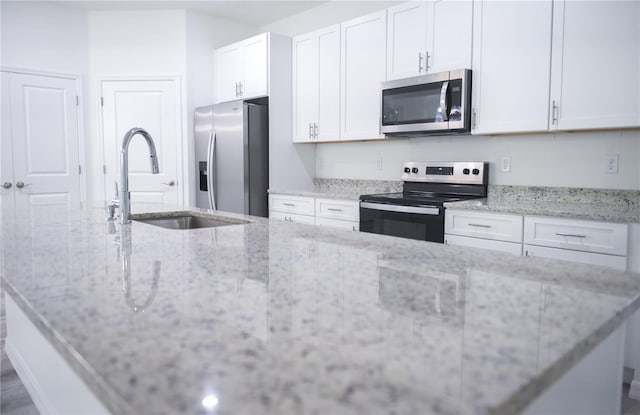 kitchen with white cabinets, sink, light stone counters, and stainless steel appliances