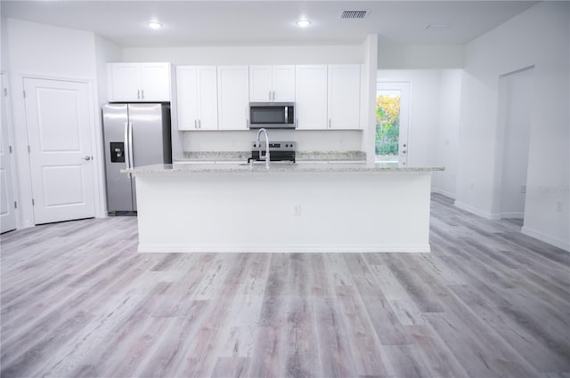 kitchen featuring light stone counters, white cabinetry, a kitchen island with sink, and appliances with stainless steel finishes