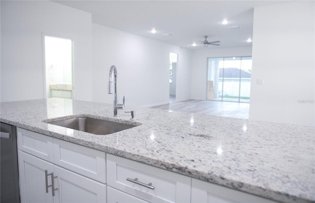 kitchen featuring light stone countertops, white cabinetry, ceiling fan, and sink