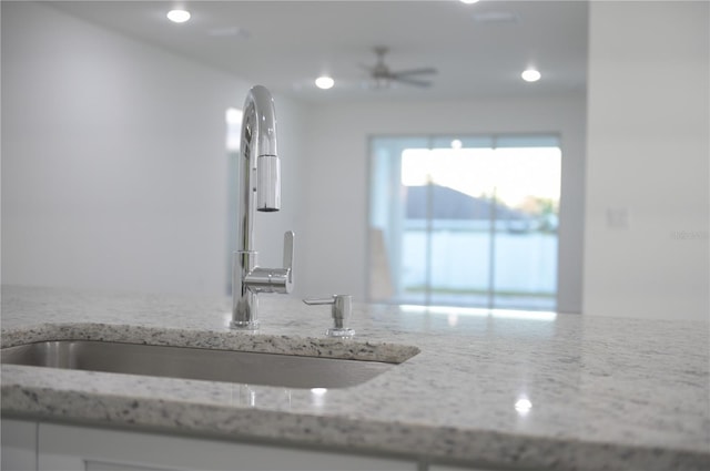 details featuring ceiling fan, light stone countertops, and sink