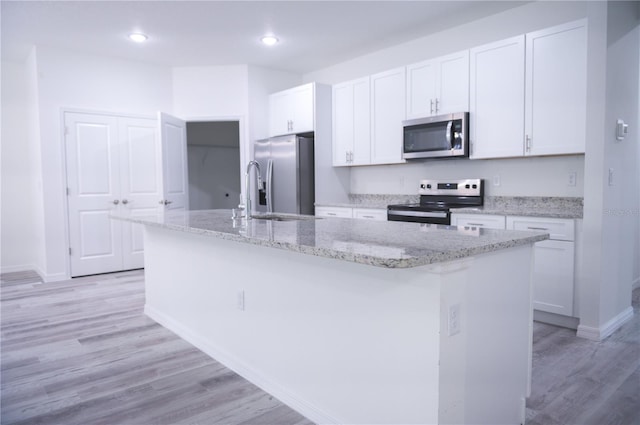 kitchen with white cabinets, light hardwood / wood-style flooring, an island with sink, and appliances with stainless steel finishes