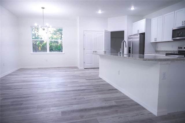 kitchen featuring pendant lighting, light hardwood / wood-style floors, white cabinetry, and stainless steel appliances