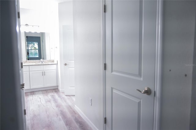 corridor with light wood-type flooring and sink