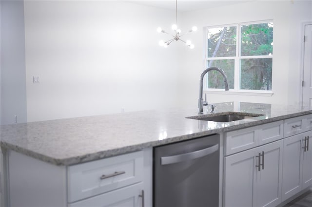 kitchen with pendant lighting, an inviting chandelier, sink, stainless steel dishwasher, and light stone countertops