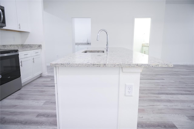 kitchen with a kitchen island with sink, white cabinets, sink, light stone countertops, and appliances with stainless steel finishes