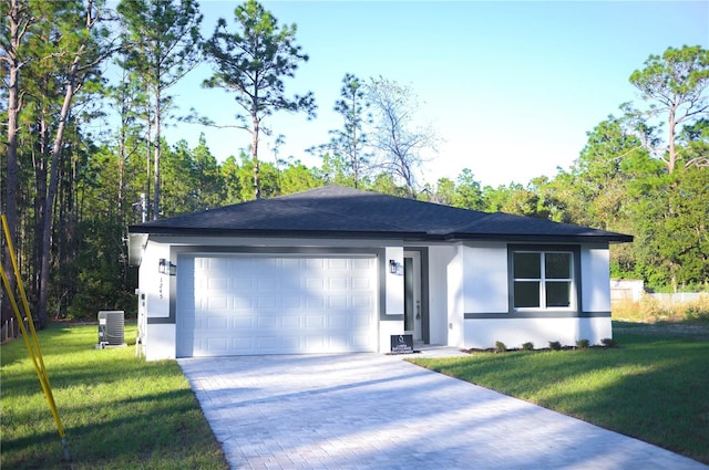 view of front of home with a front yard, a garage, and cooling unit