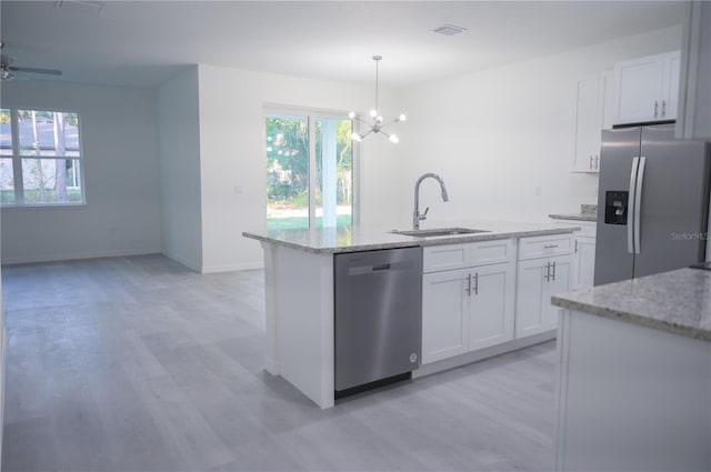 kitchen with appliances with stainless steel finishes, a kitchen island with sink, sink, pendant lighting, and white cabinets