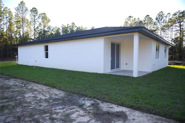 view of side of home featuring a patio and a lawn