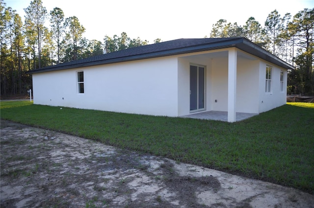 view of side of property featuring a patio and a lawn