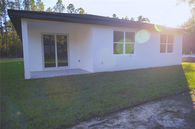 back of house featuring a lawn and a patio