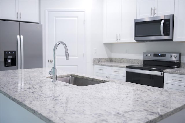 kitchen featuring white cabinetry, light stone counters, sink, and appliances with stainless steel finishes