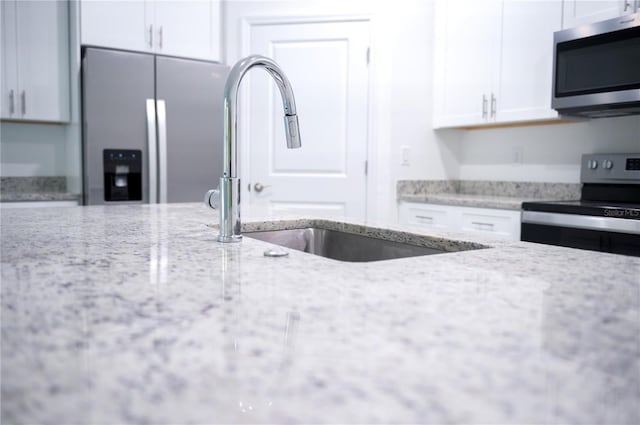 kitchen featuring white cabinetry, light stone countertops, sink, and stainless steel appliances