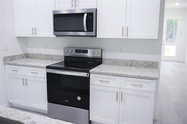 kitchen with white cabinetry, light stone counters, and appliances with stainless steel finishes