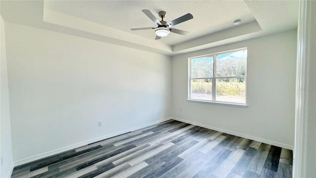 unfurnished room featuring hardwood / wood-style floors, a raised ceiling, and a textured ceiling