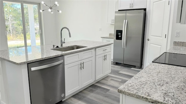 kitchen featuring white cabinets, sink, stainless steel appliances, and a kitchen island with sink