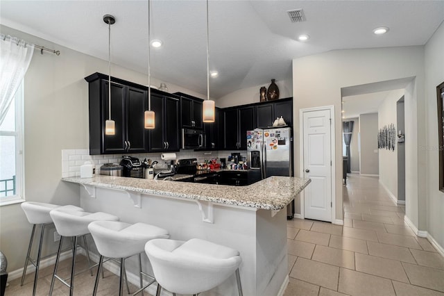 kitchen featuring a kitchen bar, pendant lighting, vaulted ceiling, backsplash, and stainless steel appliances