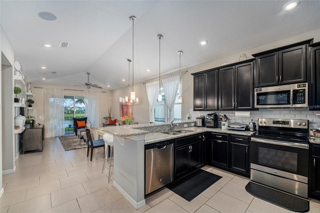 kitchen with sink, hanging light fixtures, lofted ceiling, light tile patterned floors, and appliances with stainless steel finishes