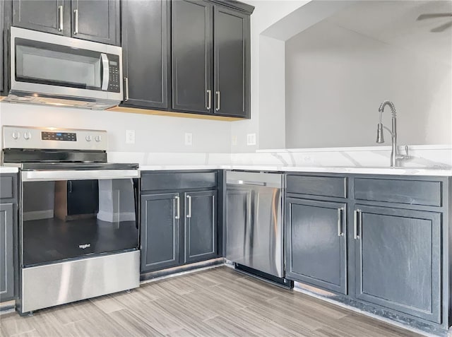 kitchen featuring sink, light stone counters, light hardwood / wood-style floors, and stainless steel appliances