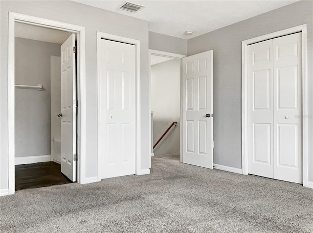 unfurnished bedroom featuring two closets and dark carpet