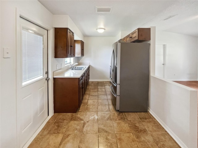 kitchen featuring stainless steel fridge, sink, and lofted ceiling