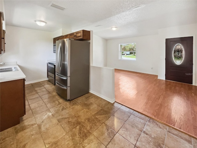 kitchen with stainless steel appliances, a textured ceiling, sink, and light hardwood / wood-style flooring