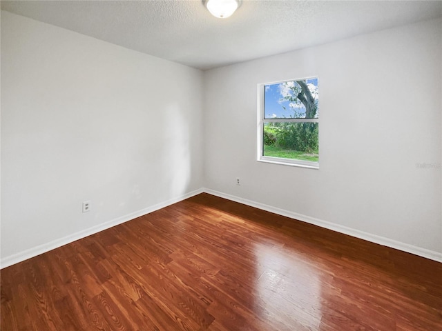 empty room with hardwood / wood-style floors and a textured ceiling