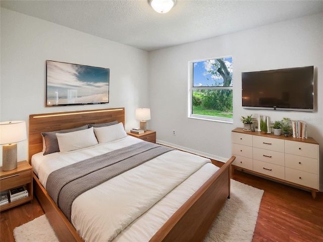 bedroom featuring dark hardwood / wood-style flooring and a textured ceiling