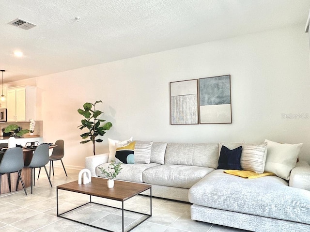 living room with a textured ceiling and light tile patterned floors