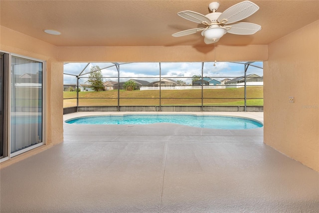 view of pool with a patio, glass enclosure, and ceiling fan