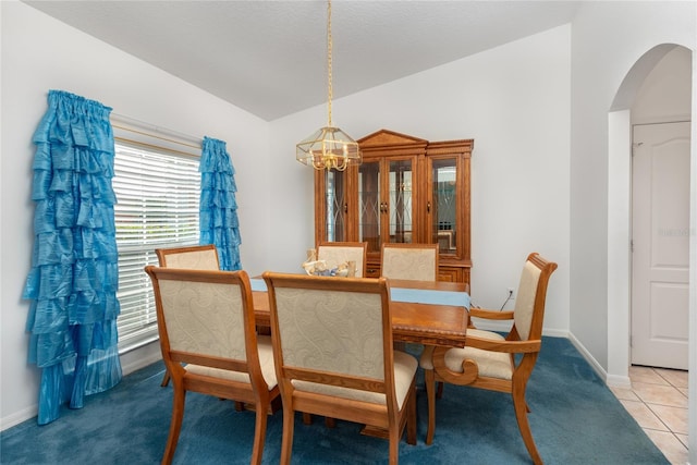 dining space with vaulted ceiling, a notable chandelier, and light tile patterned floors