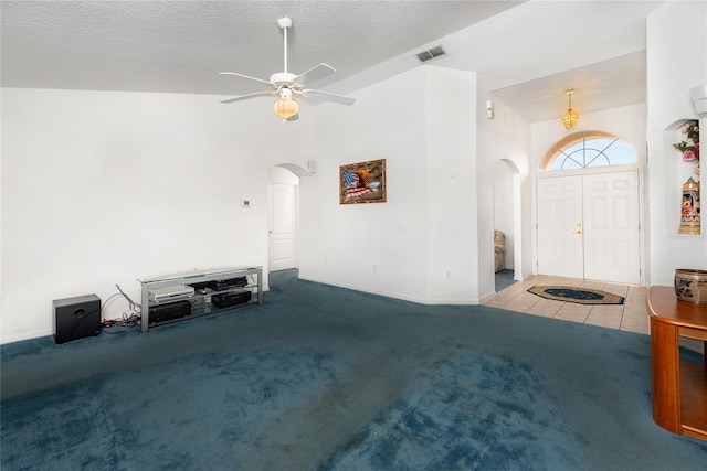 unfurnished living room featuring ceiling fan, a textured ceiling, high vaulted ceiling, and light colored carpet