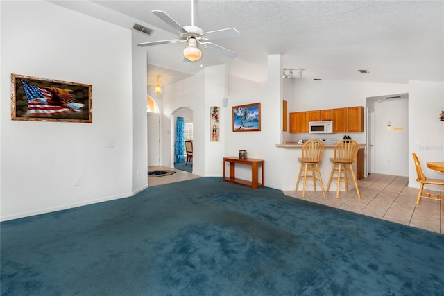 living room featuring ceiling fan, a textured ceiling, light carpet, and lofted ceiling