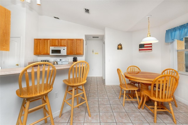 kitchen with a kitchen breakfast bar, light tile patterned flooring, hanging light fixtures, and lofted ceiling