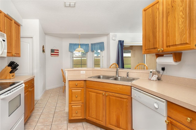 kitchen featuring white appliances, plenty of natural light, sink, and pendant lighting