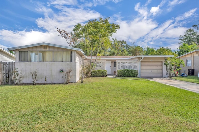 view of front of home featuring a garage, cooling unit, and a front yard