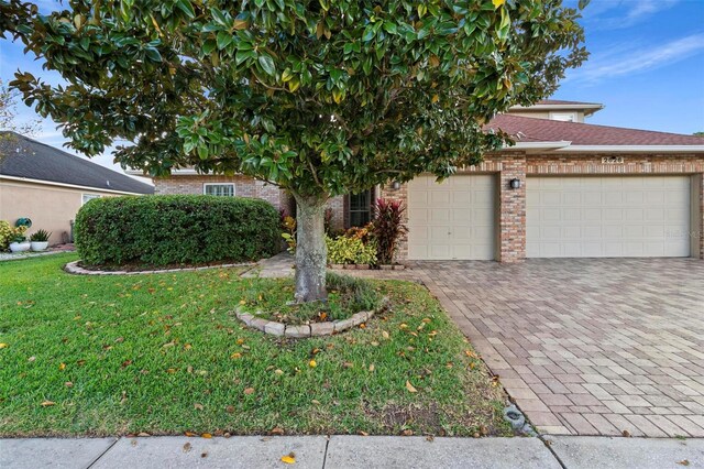 2626 Raccoon Run Ln, Orlando, FL 32837 - view of property hidden behind natural elements with brick siding, a front yard, a garage, and driveway