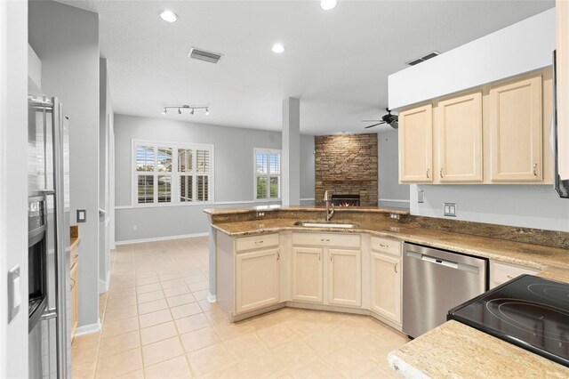 2626 Raccoon Run Ln, Orlando, FL 32837 - kitchen with stainless steel dishwasher, a sink, ceiling fan, a peninsula, and a stone fireplace