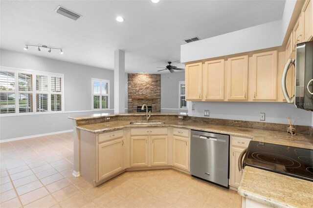 2626 Raccoon Run Ln, Orlando, FL 32837 - kitchen featuring stainless steel appliances, a sink, ceiling fan, a peninsula, and a stone fireplace