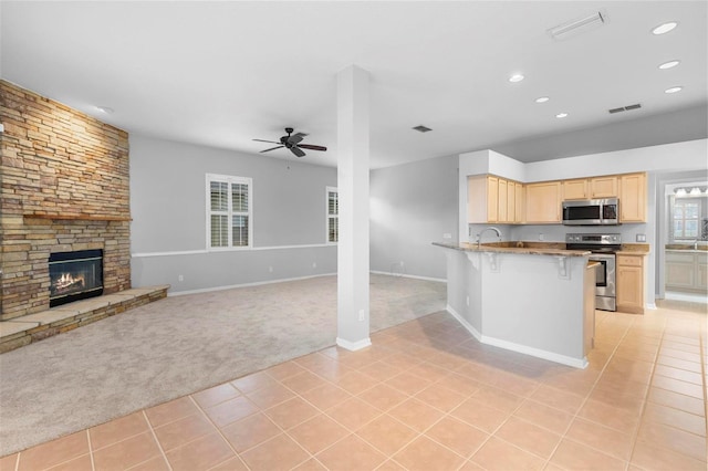 2626 Raccoon Run Ln, Orlando, FL 32837 - kitchen featuring appliances with stainless steel finishes, light brown cabinetry, light colored carpet, a kitchen breakfast bar, and light tile patterned flooring