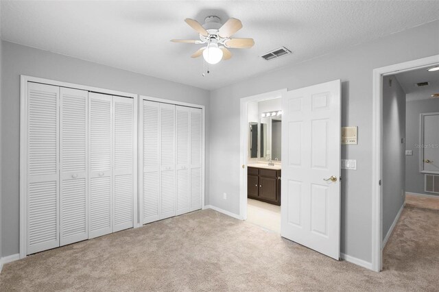 2626 Raccoon Run Ln, Orlando, FL 32837 - unfurnished bedroom with light colored carpet, multiple closets, baseboards, a sink, and connected bathroom