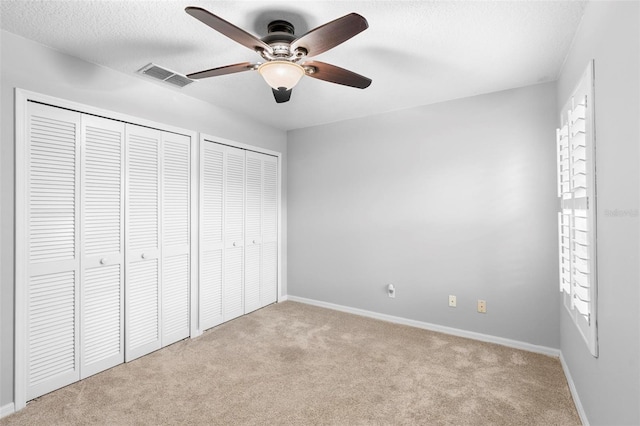 2626 Raccoon Run Ln, Orlando, FL 32837 - unfurnished bedroom featuring carpet flooring, two closets, baseboards, a textured ceiling, and a ceiling fan