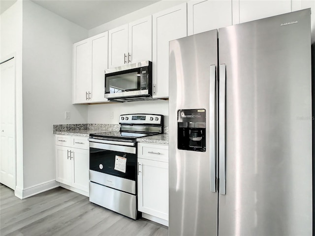 kitchen featuring appliances with stainless steel finishes, white cabinets, light stone countertops, and light hardwood / wood-style floors