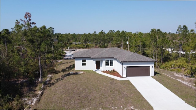 single story home with stucco siding, an attached garage, a wooded view, driveway, and a front lawn