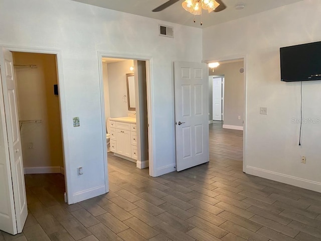 unfurnished bedroom featuring ensuite bath, ceiling fan, a spacious closet, dark hardwood / wood-style floors, and a closet