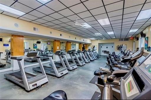 gym featuring concrete flooring, a paneled ceiling, and ceiling fan