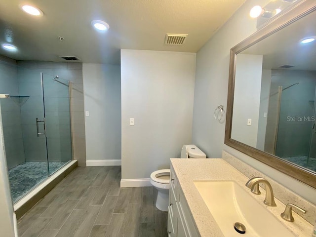 bathroom featuring hardwood / wood-style floors, vanity, toilet, and walk in shower