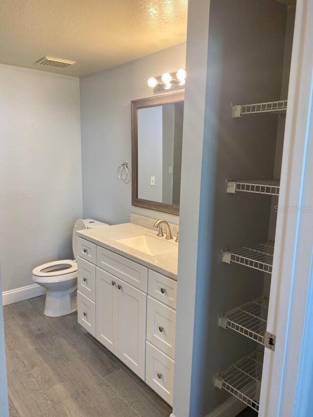 3468 Soho St Unit 107, Orlando, FL 32835 - bathroom featuring toilet, wood finished floors, vanity, a textured ceiling, and baseboards